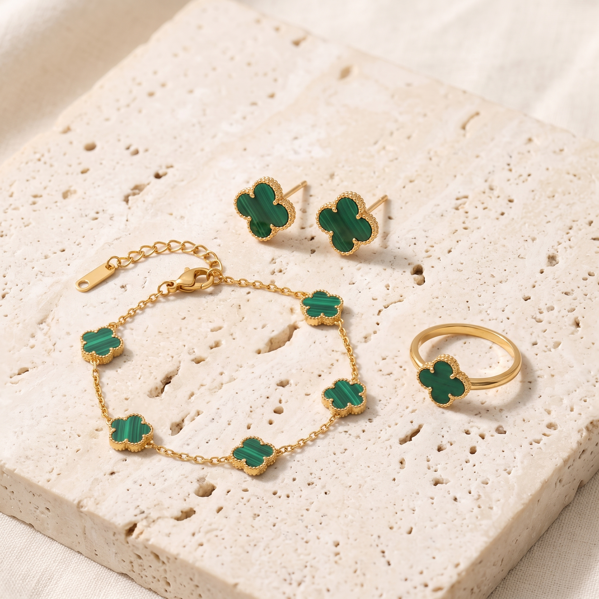 The Clover Trio — bracelet, studs and ring on travertine