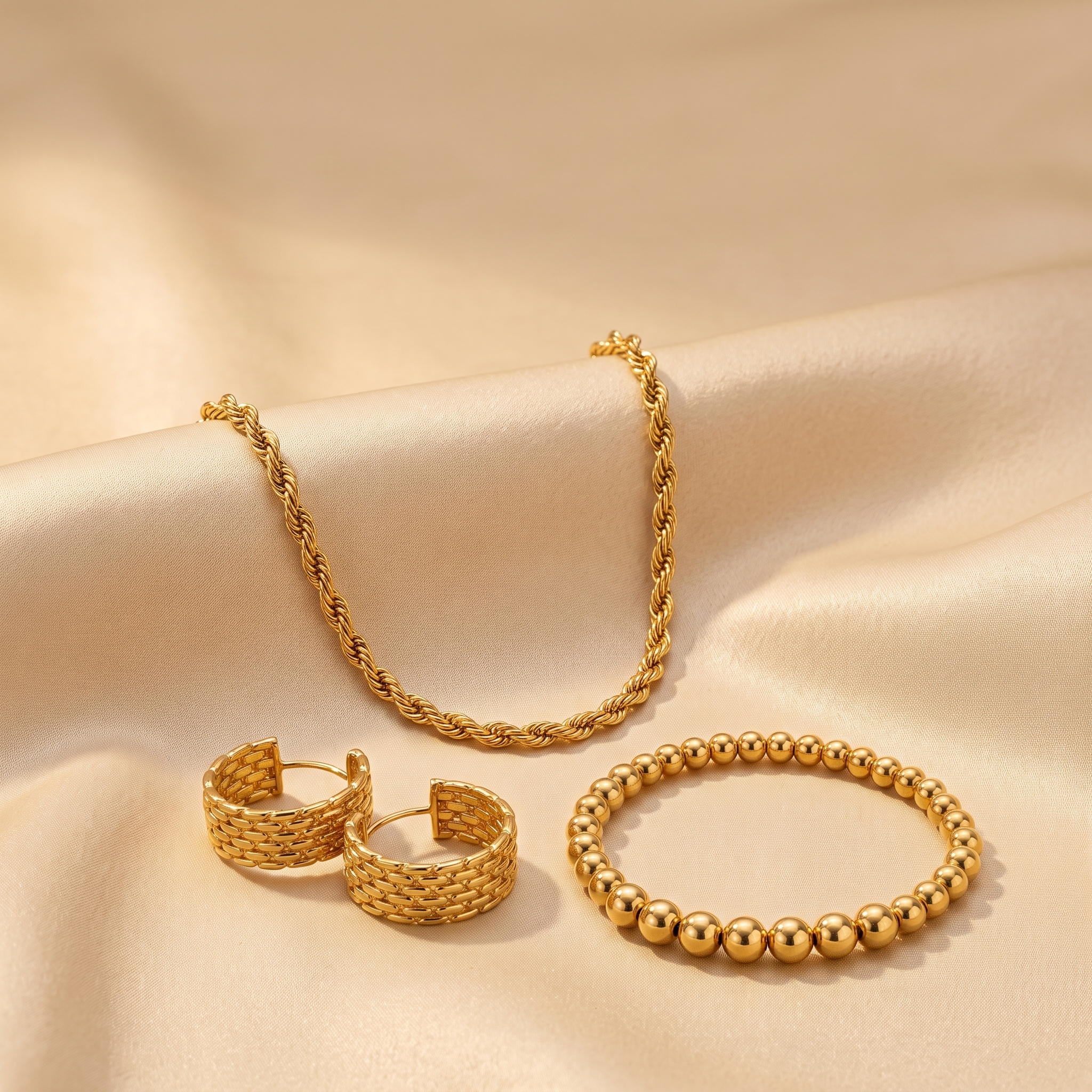The Gold Standard Trio — rope chain, hoops and stretch bracelet on champagne satin